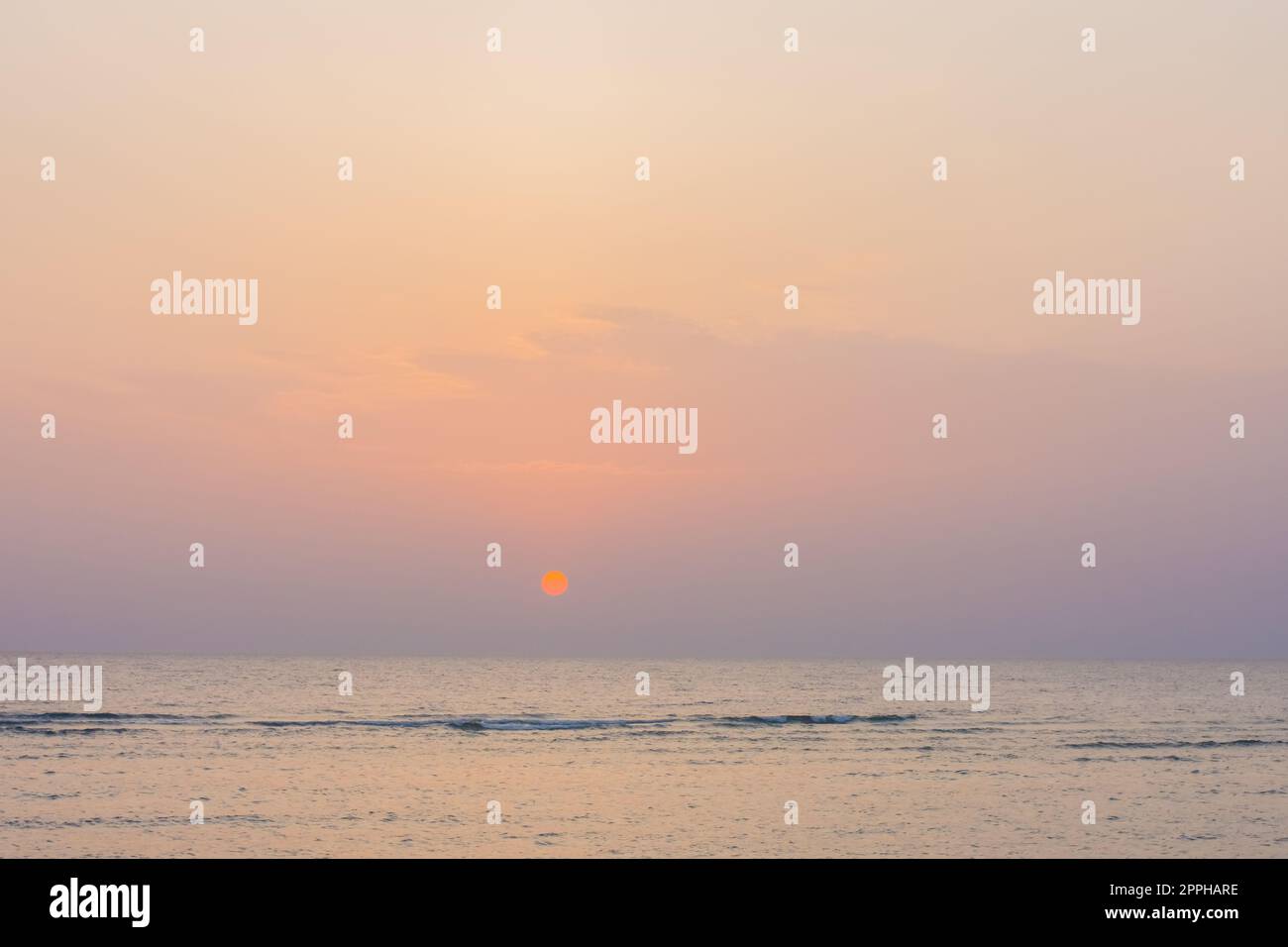 incredibile alba con sole arancione caldo e cielo colorato sul mare Foto Stock