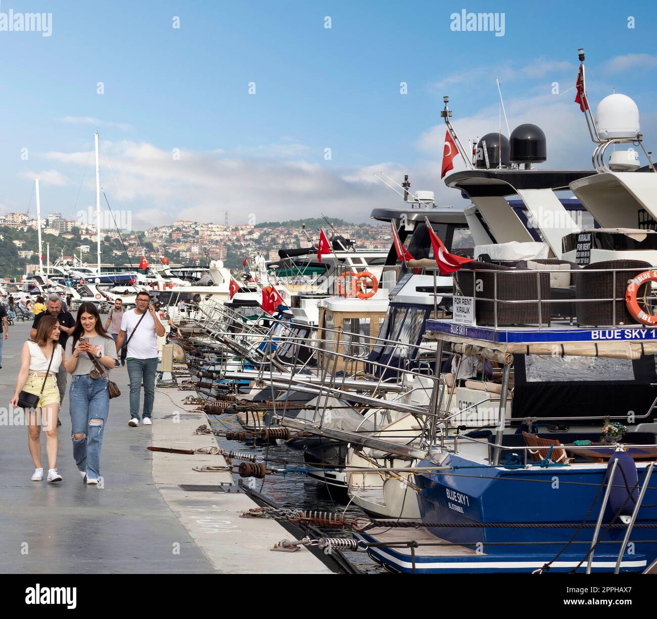Persone che camminano lungo il Bosforo tra i quartieri di Bebek e Hisari, accanto a barche e yacht attraccati, Istanbul, Turchia Foto Stock