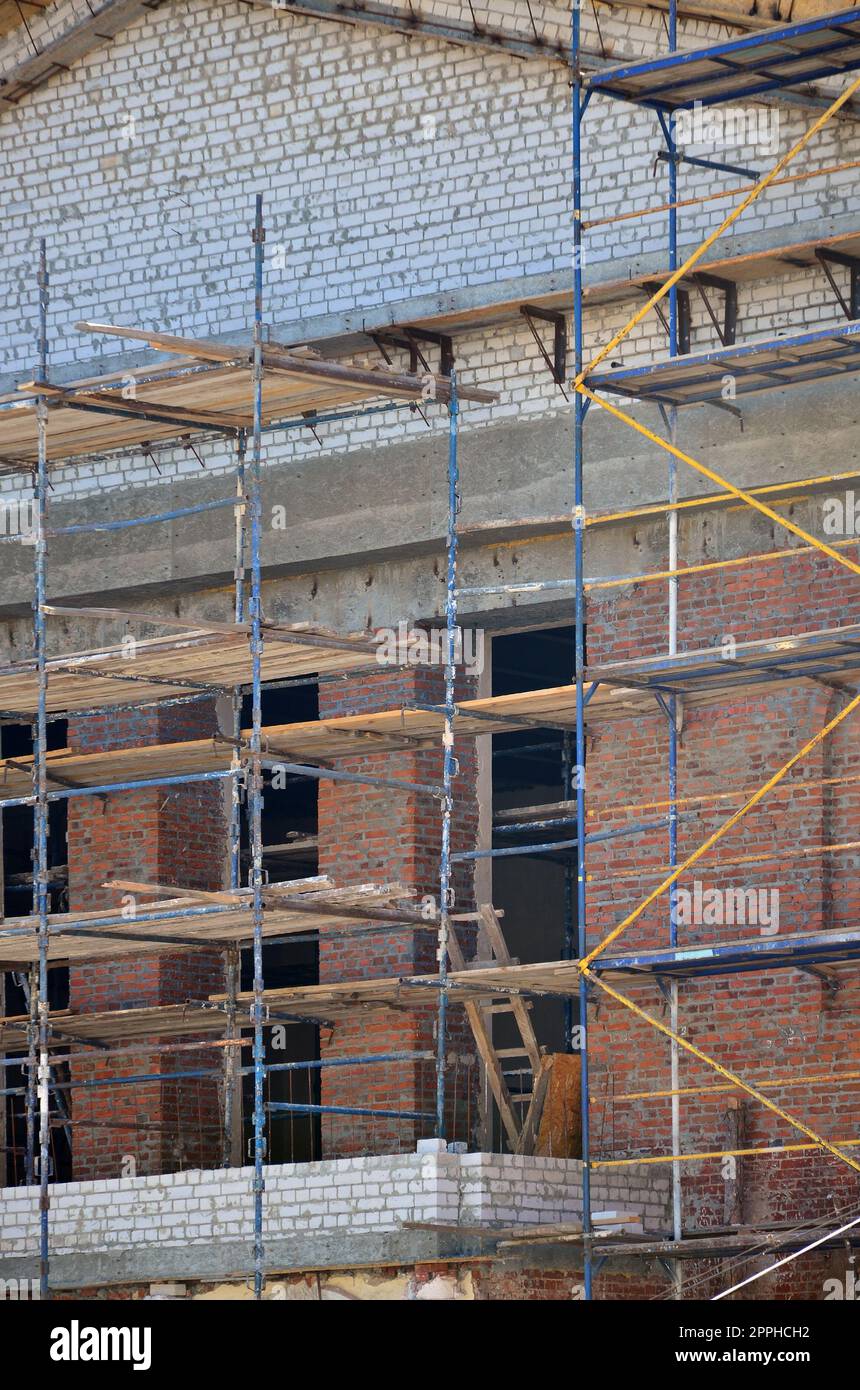 Scaffolds installato vicino a più piani in mattoni in costruzione Foto Stock