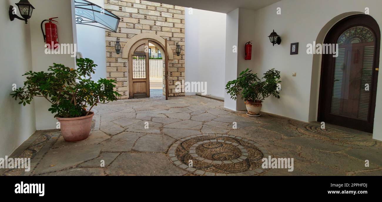 Grande entrata in una vecchia casa con piante verdi e pareti in mattoni. Foto Stock