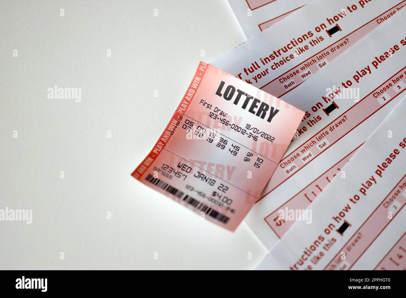Il biglietto della lotteria rossa si trova su fogli da gioco rosa con i numeri da contrassegnare per giocare alla lotteria. Concetto di gioco alla lotteria o dipendenza dal gioco d'azzardo. Primo piano Foto Stock