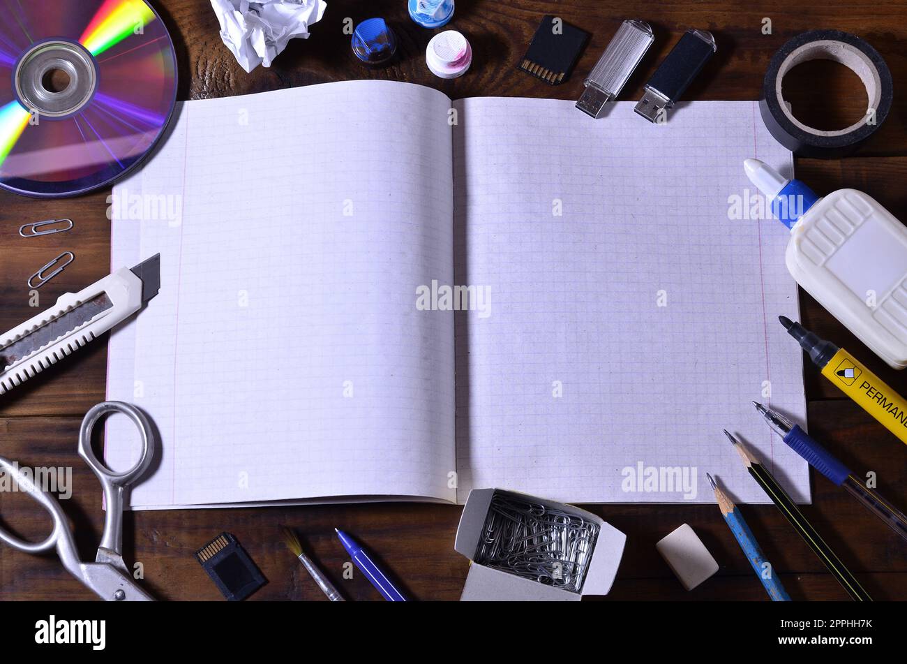 Una scuola o un ufficio ancora vita con un taccuino o un libro di controllo aperto della scuola e molte forniture per ufficio. Le forniture scolastiche giacciono su uno sfondo di legno marrone. Posiziona per il testo Foto Stock