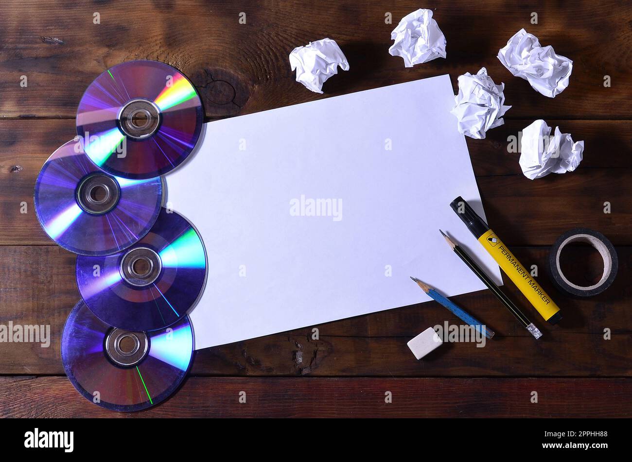 Una scuola o un ufficio ancora in vita con un foglio bianco di carta e molte forniture per ufficio. Le forniture scolastiche giacciono su uno sfondo di legno marrone. Posiziona per il testo Foto Stock