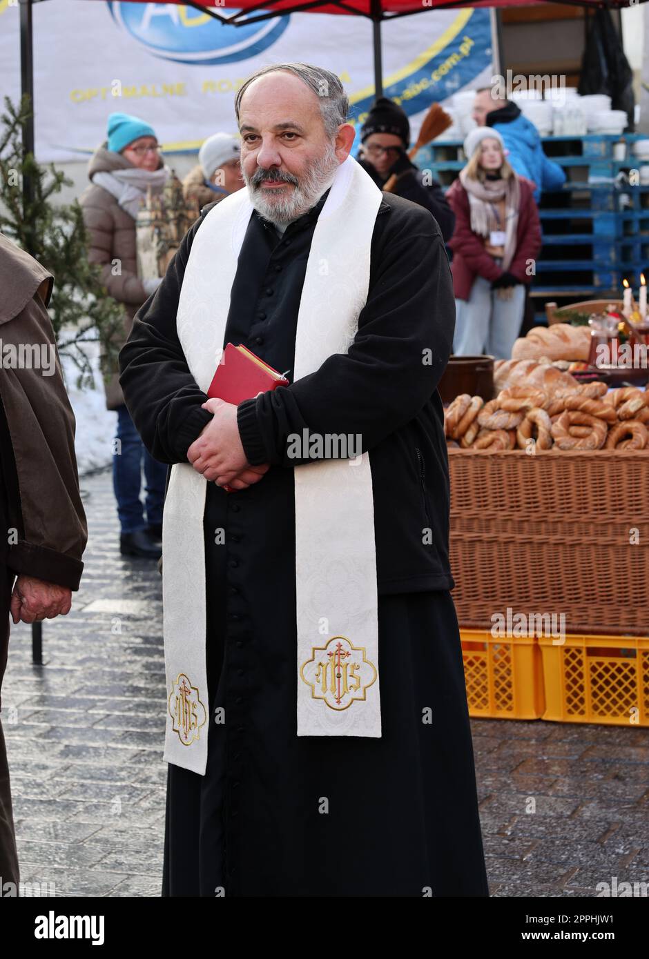 Il sacerdote Tadeusz Isakowicz-Zaleski benedice i tradizionali piatti di Natale polacchi che vengono presentati nella piazza principale durante la vigilia di Natale per i poveri e i senzatetto Foto Stock