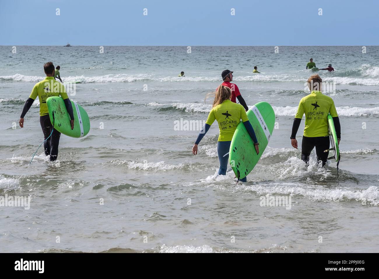 I vacanzieri che prendono parte a una lezione di surf con un istruttore a Fistral Beach a Newquay in Cornovaglia nel Regno Unito. Foto Stock