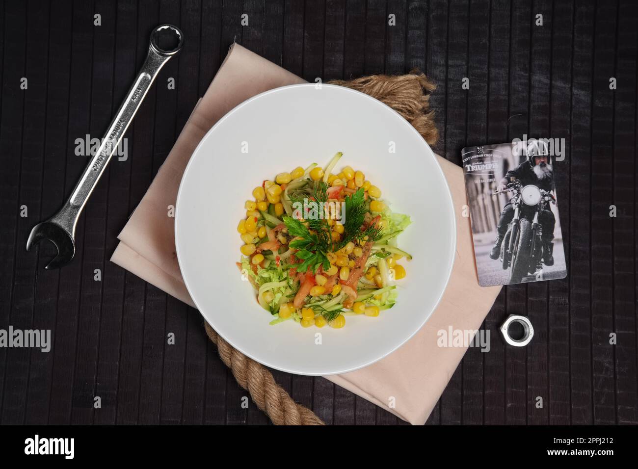 Insalata con mais, pomodoro, cetriolo e cavolo sul tavolo vicino alla chiave e alla vite-dado. Vista dall'alto. Foto Stock