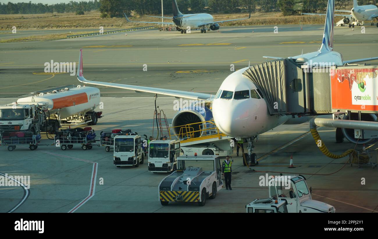 Cipro, Larnaca - 12 ottobre 2022: L'aereo e' al braccio estraibile dell'aeroporto. Preparazione di un volo: Velivolo con ponte di imbarco passeggeri attaccato Foto Stock