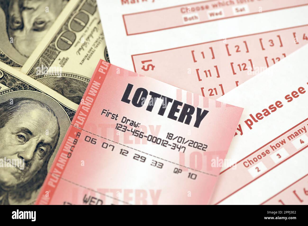 Il biglietto della lotteria rossa si trova su fogli da gioco rosa con numeri da segnare su banconote da cento dollari. Concetto di gioco alla lotteria o dipendenza dal gioco d'azzardo. Primo piano Foto Stock