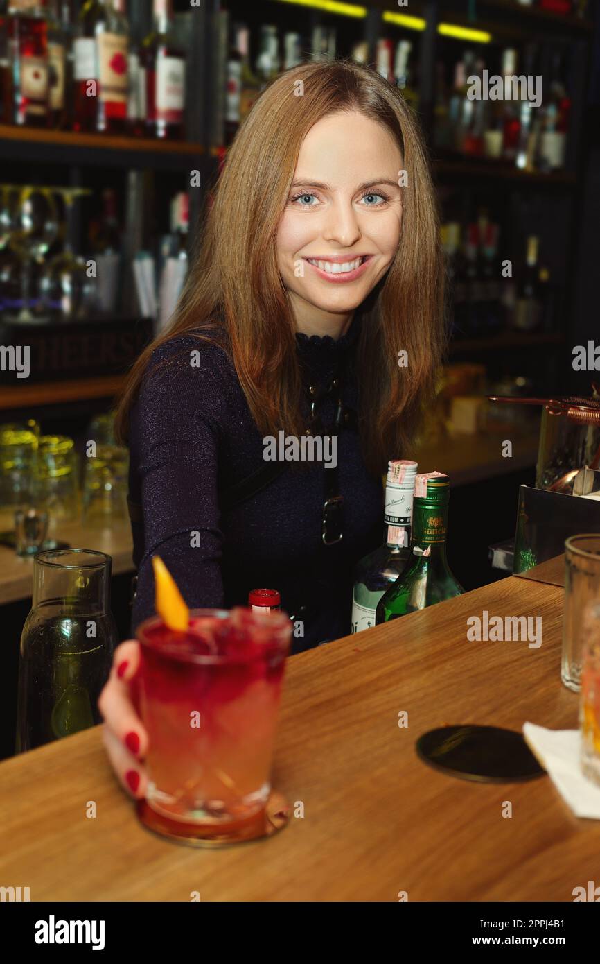 Barista ragazza che serve cocktail a un cliente Foto Stock