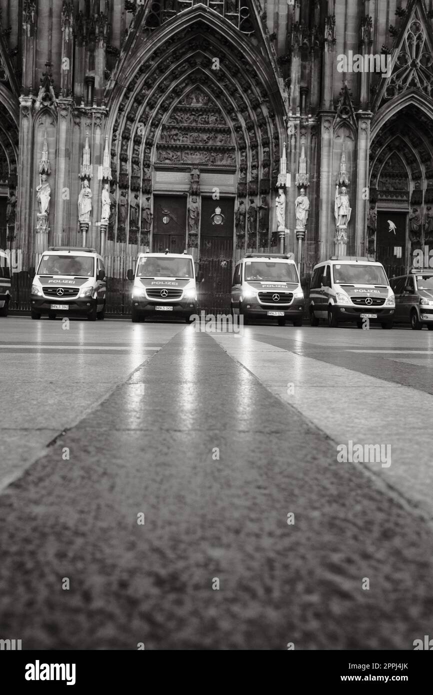 Immagine in scala di grigi della fila di auto della polizia Mercedes-Benz Sprinter di fronte alla Cattedrale di Colonia in Germania Foto Stock Immagine in scala di grigi della fila di auto della polizia Mercedes-Benz Sprinter di fronte alla Cattedrale di Colonia in Germania Foto Stock