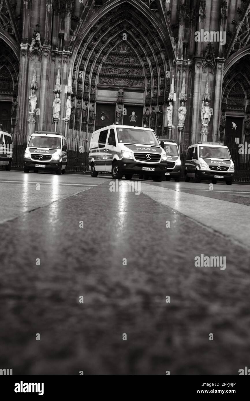 Ripresa in scala di grigi di molte auto della polizia Mercedes-Benz Sprinter di fronte alla Cattedrale di Colonia in Germania Foto Stock Ripresa in scala di grigi di molte auto della polizia Mercedes-Benz Sprinter di fronte alla Cattedrale di Colonia in Germania Foto Stock