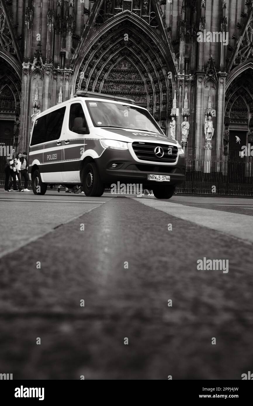 Ripresa in scala di grigi di una macchina della polizia Mercedes-Benz Sprinter di fronte alla Cattedrale di Colonia in Germania Foto Stock Ripresa in scala di grigi di una macchina della polizia Mercedes-Benz Sprinter di fronte alla Cattedrale di Colonia in Germania Foto Stock