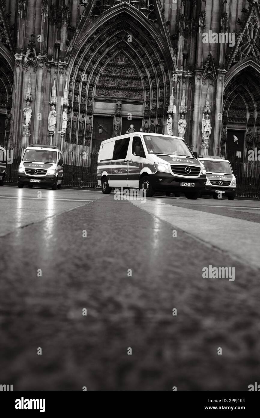 Ripresa in scala di grigi di molte auto della polizia Mercedes-Benz Sprinter di fronte alla Cattedrale di Colonia in Germania Foto Stock Ripresa in scala di grigi di molte auto della polizia Mercedes-Benz Sprinter di fronte alla Cattedrale di Colonia in Germania Foto Stock