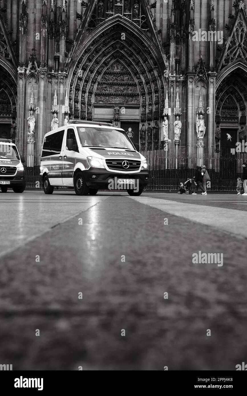 Ripresa in scala di grigi di una macchina della polizia Mercedes-Benz Sprinter di fronte alla Cattedrale di Colonia in Germania Foto Stock Ripresa in scala di grigi di una macchina della polizia Mercedes-Benz Sprinter di fronte alla Cattedrale di Colonia in Germania Foto Stock