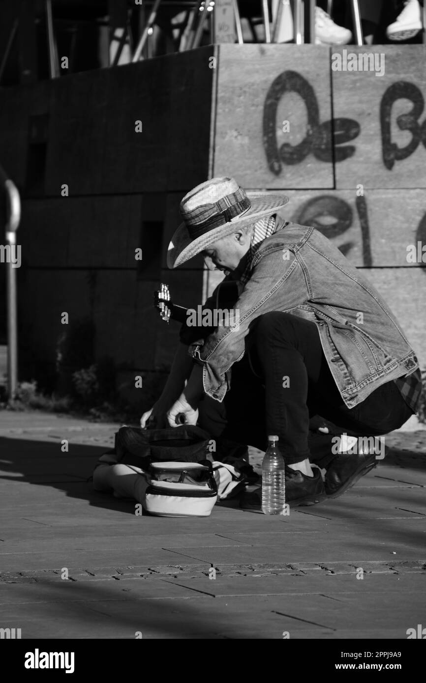 Musicista di strada in un cappello che disimballa la sua chitarra a Duesseldorf, Germania Foto Stock