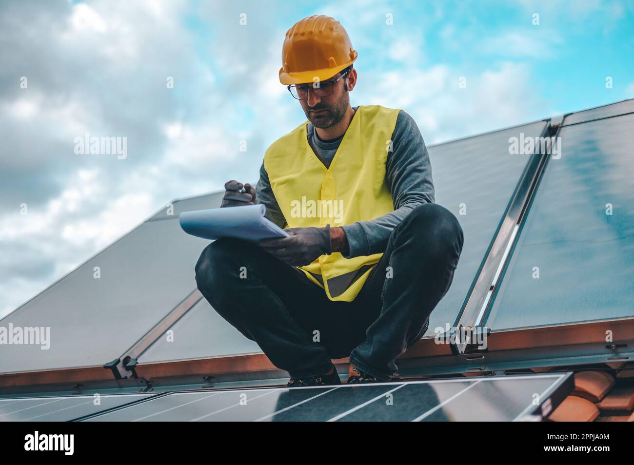 L'uomo lavora su un sistema di energia rinnovabile con pannello solare per l'elettricità e l'acqua calda Foto Stock