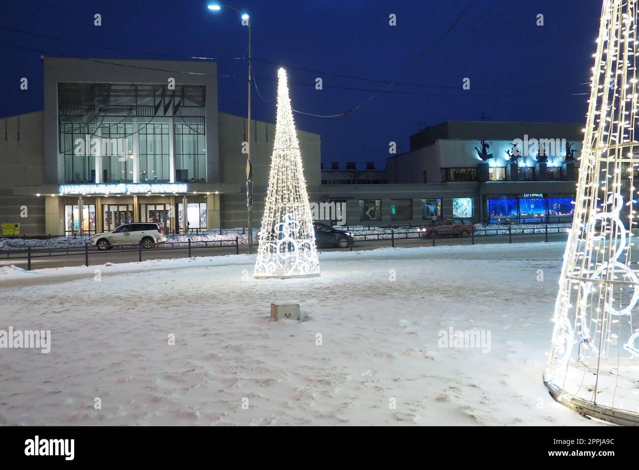 Petrozavodsk, Carelia, Russia, 5 gennaio 2023. Il trambusto di Capodanno. Ghirlande - alberi di Natale e lampade. Auto e persone attraversano la neve. Karl Marx Avenue. Teatro Nazionale finlandese Foto Stock