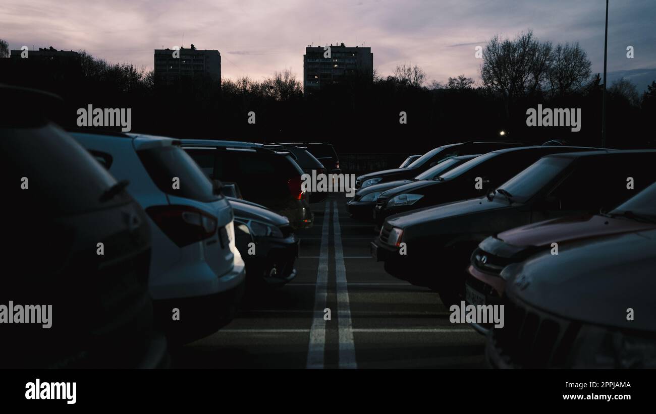 auto parcheggiate in fila nel parcheggio all'aperto al buio con strisce di rullini tra di loro Foto Stock