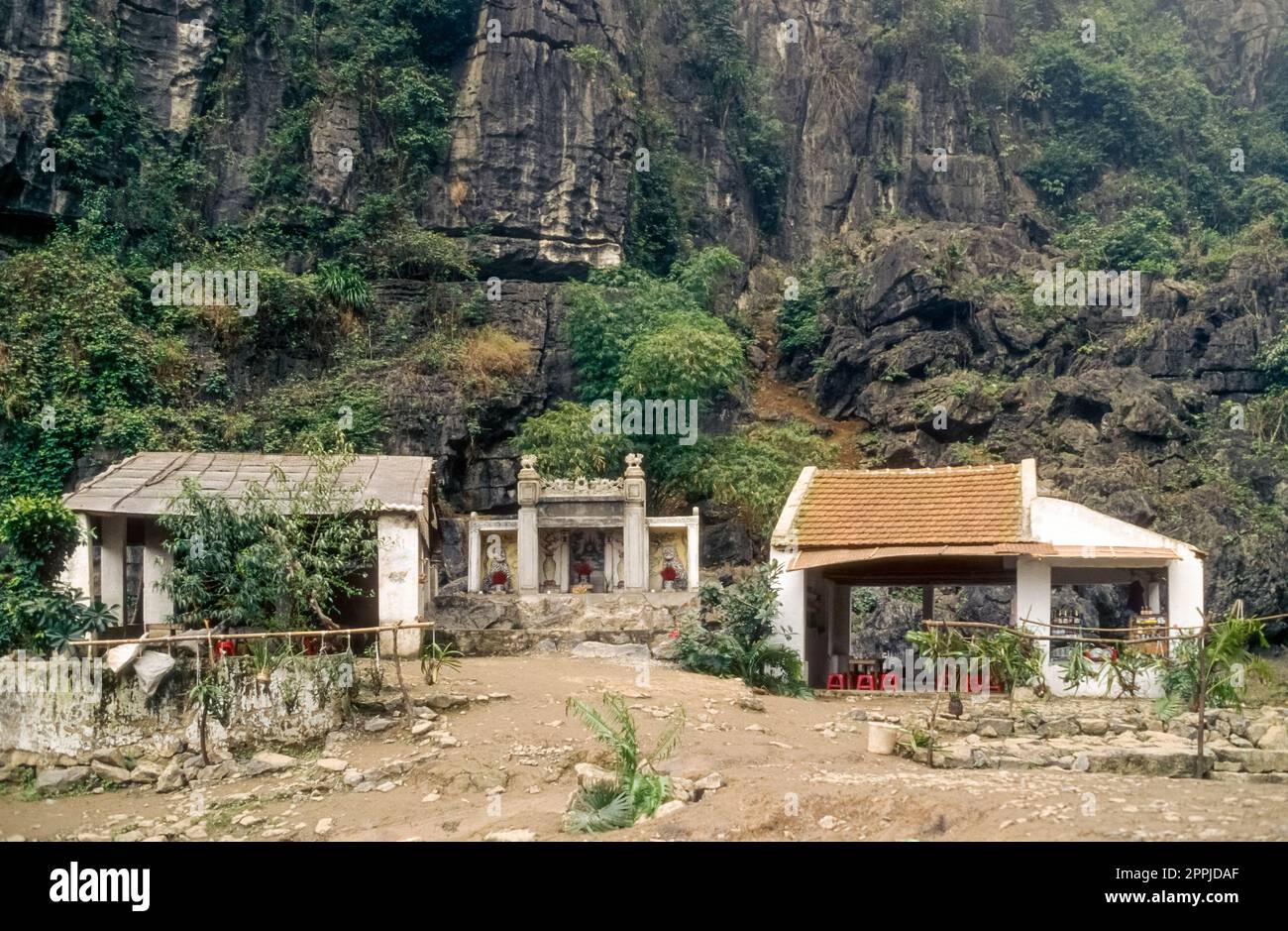 Scannerizzata di una fotografia storica a colori di un complesso di templi buddisti ai piedi di una roccia nel nord del Vietnam Foto Stock