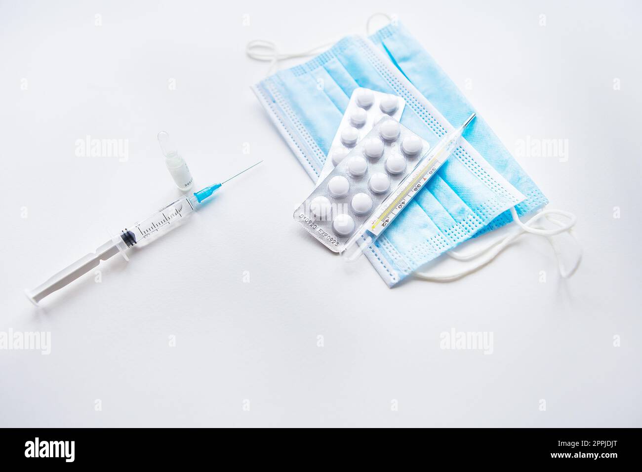 Preparazione per la vaccinazione contro la covid-19. Termometro, pillole, maschera medica su un tavolo bianco. Consente di inserire un'iscrizione, una foto orizzontale. Foto Stock