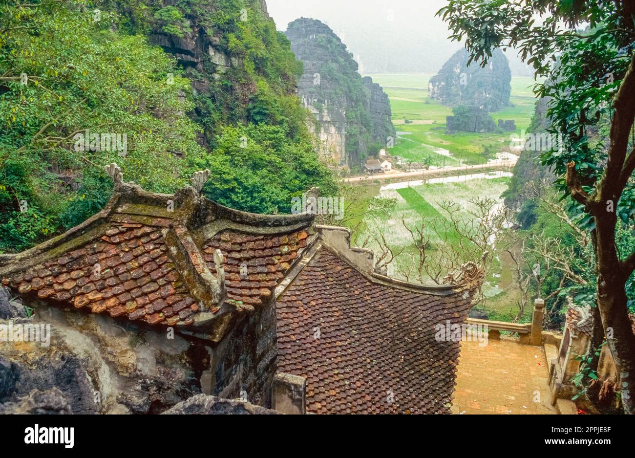 Scannerizzata di una fotografia storica a colori di un complesso di templi buddisti ai piedi di una roccia nel nord del Vietnam Foto Stock