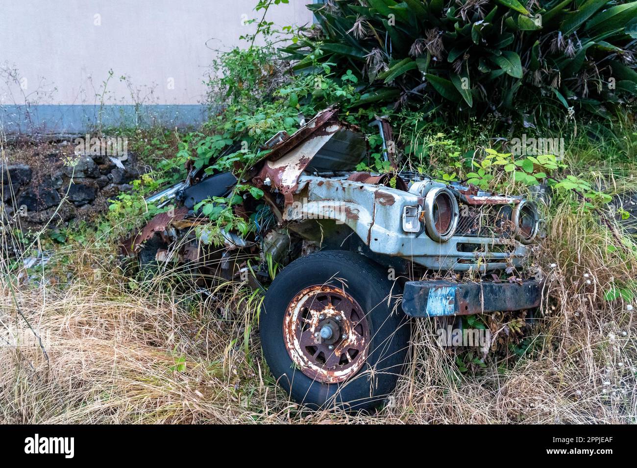 Auto abbandonata lasciata vicino al muro Foto Stock