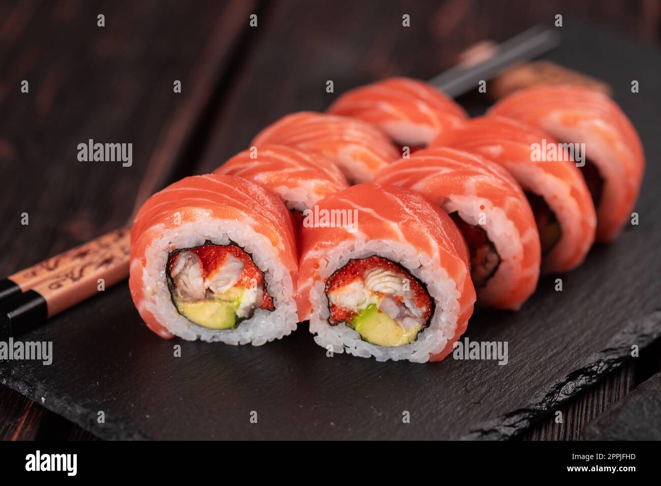 Maguro di sushi con tonno, anguilla affumicata, avocado, formaggio philadelphia su tavola nera da vicino. Menu sushi. Cucina giapponese. Foto Stock