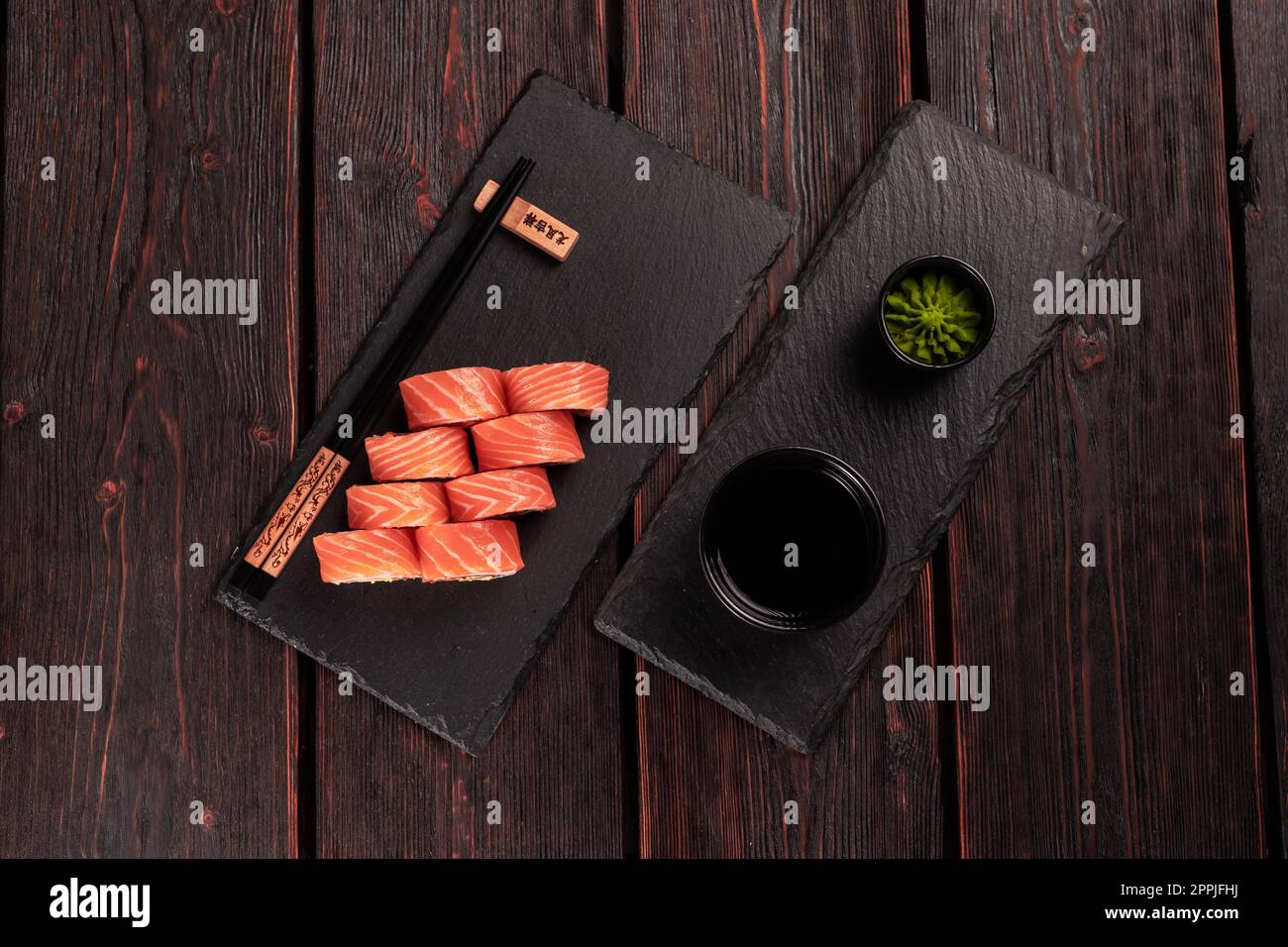 Maguro di sushi con tonno, anguilla affumicata, avocado, formaggio philadelphia sulla tavola nera vista dall'alto. Menu sushi. Cucina giapponese. Foto Stock
