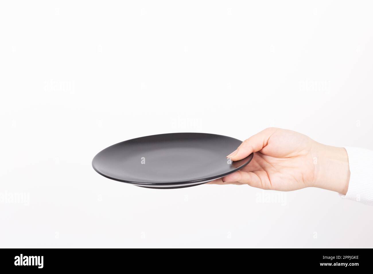 un piatto nero vuoto è presentato da una mano femminile Foto Stock