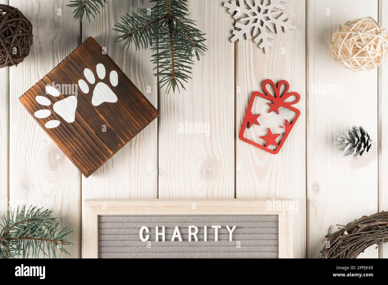 Tavola in legno con composizione creativa festiva con simbolo zampa animale, confezione regalo e carità con decorazione a ramoscello di abete Foto Stock