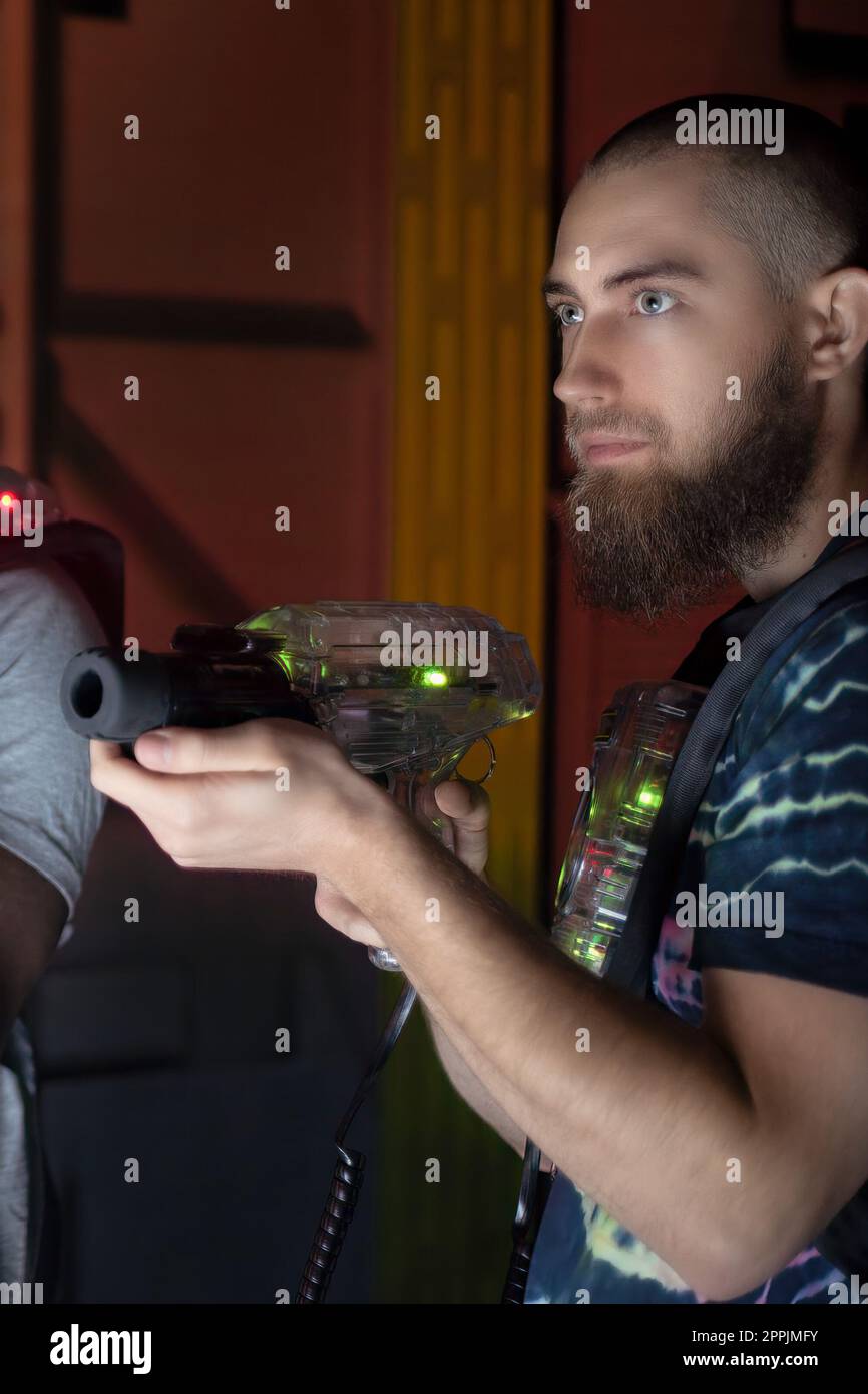 lettore laser tag con barba che tiene la pistola giocattolo nel labirinto del gioco Foto Stock
