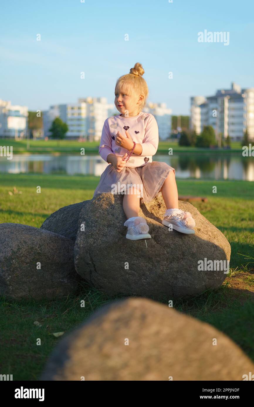 Bambino seduto sulla pietra al tramonto Foto Stock