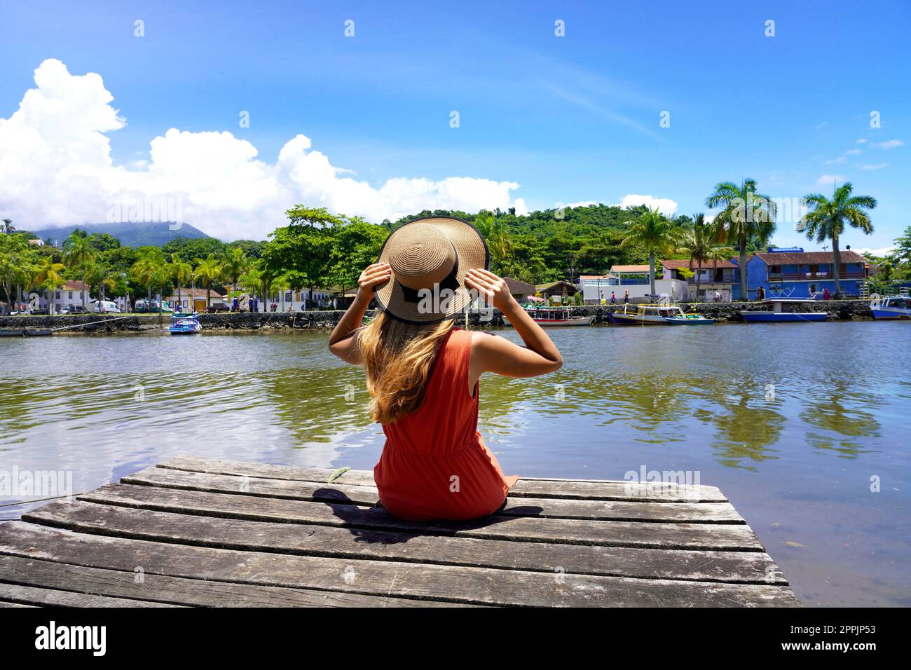 Destinazione tropicale per le vacanze. Bella giovane donna seduta sul molo di legno godendo rilassante giornata di sole ventose in Brasile. Foto Stock