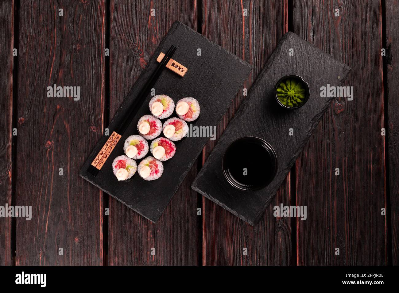 Maki sushi roll con avocado di salmone e caviale di tobiko servito sulla tavola nera vista dall'alto - cibo giapponese Foto Stock