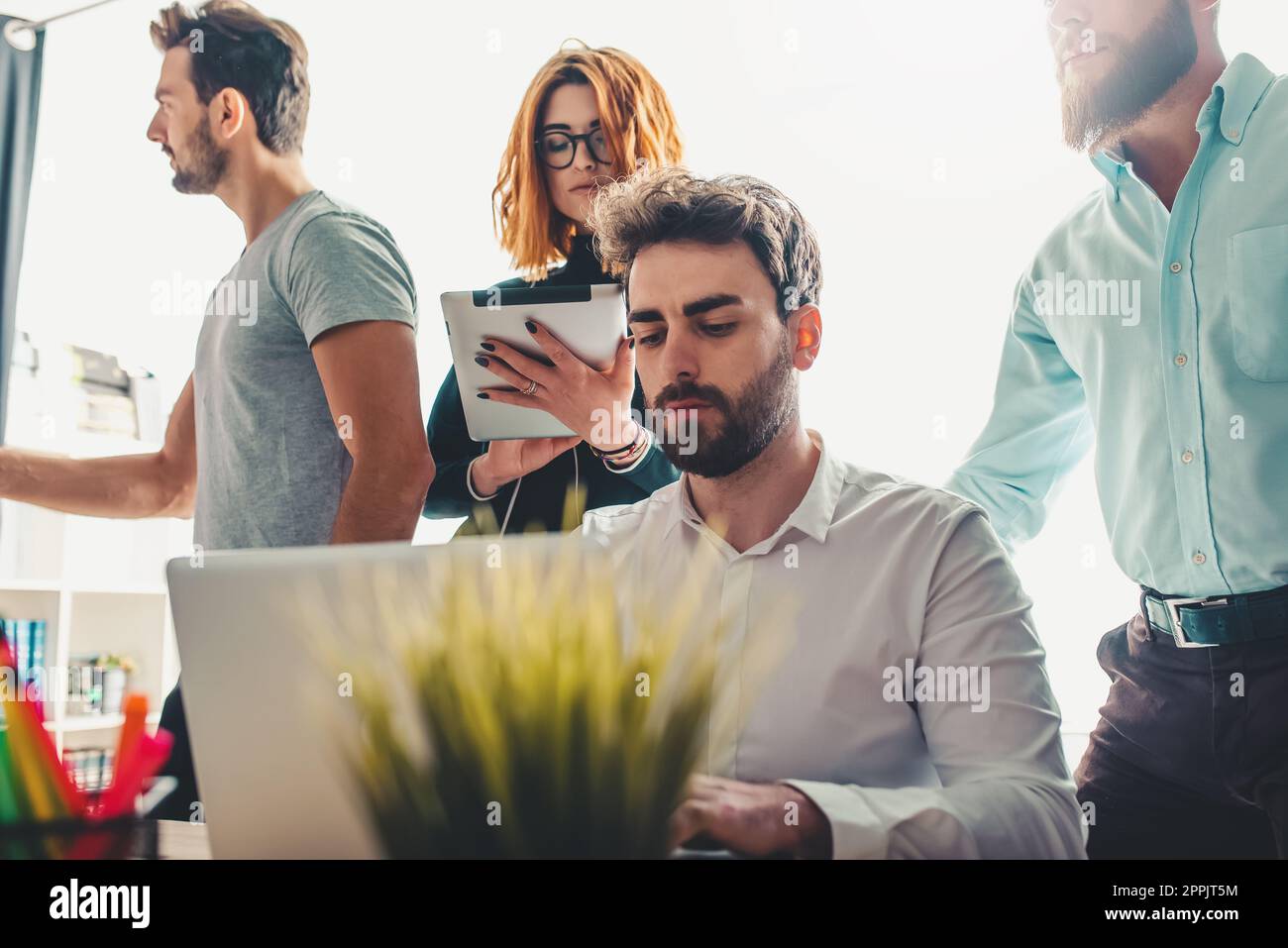 Gli uomini d'affari in ufficio lavorano insieme durante una riunione con un computer portatile Foto Stock