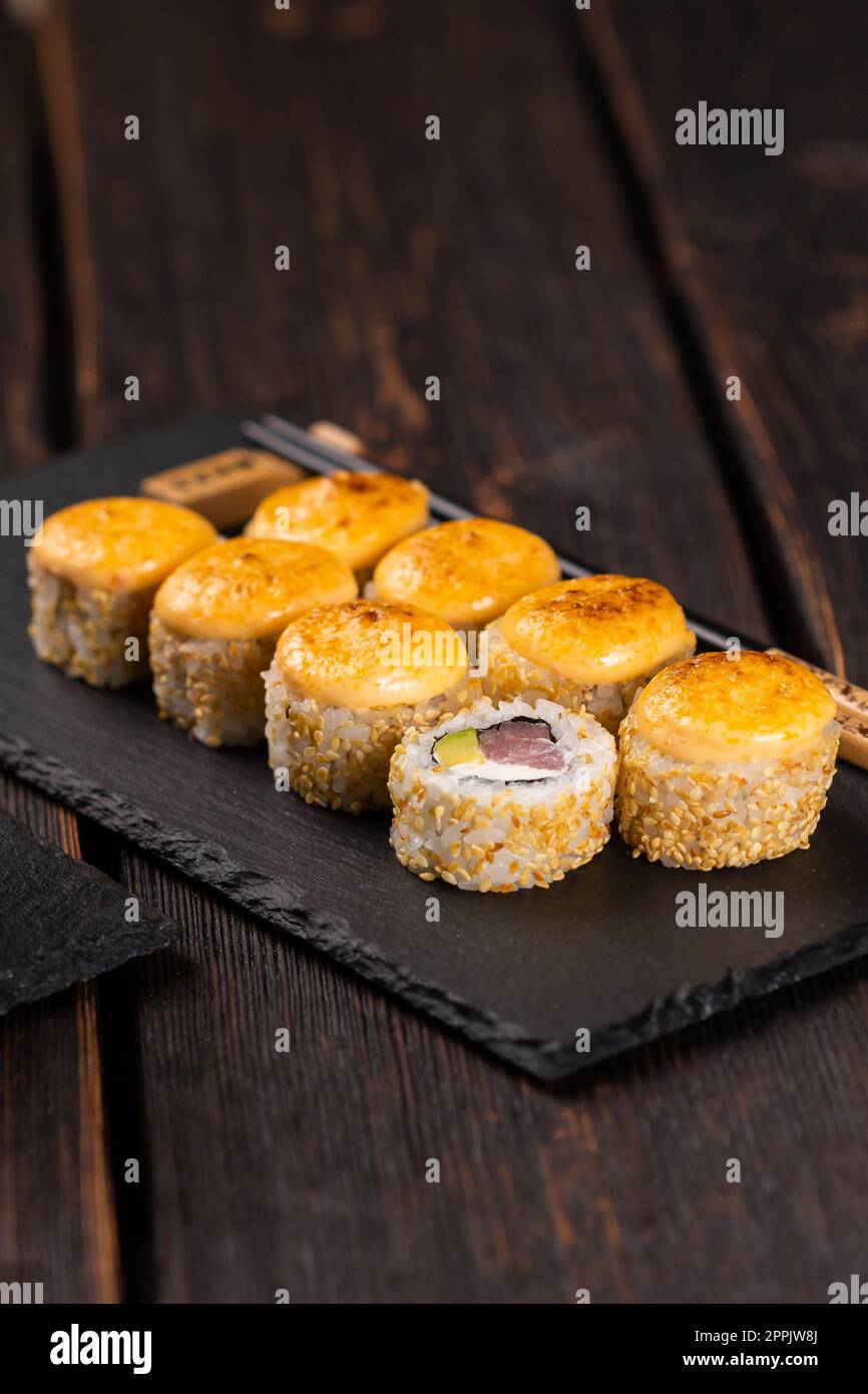 Sushi roll con tonno, avocado e caviale tobiko servito a bordo nero primo piano - cibo giapponese asiatico Foto Stock