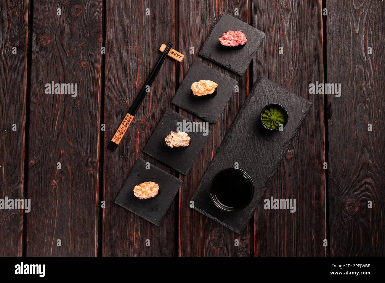 Set di Gunkan Maki Sushi con diversi tipi di salmone di pesce, capesante, persico, anguilla, gamberi e caviale su fondo di legno. Menu sushi. Sushi giapponese con vista dall'alto Foto Stock