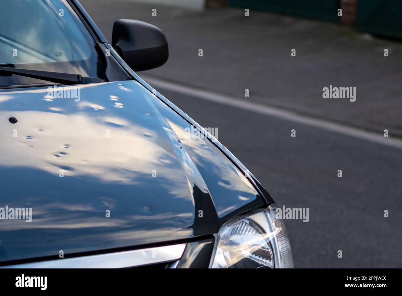 Cofano motore auto nero con molte ammaccature da grandine mostrano le forze della natura l'importanza della sostituzione dell'assicurazione auto assicurazione del valore contro le ammaccature da grandine dei pericoli di tempesta condizioni meteorologiche estreme Foto Stock