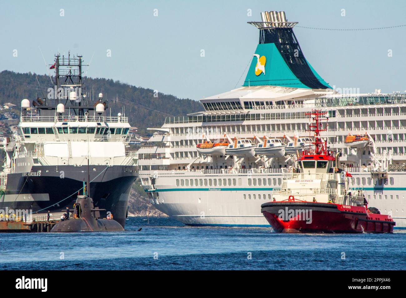 Scena del porto a Bergen, Norvegia, con nave da crociera, rimorchiatore e sottomarino Foto Stock