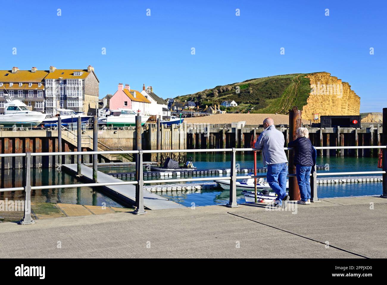 Coppia anziana sul lungomare che guarda alla vista delle scogliere Jurassic Coast, West Bay, Dorset, UK, Europa Foto Stock