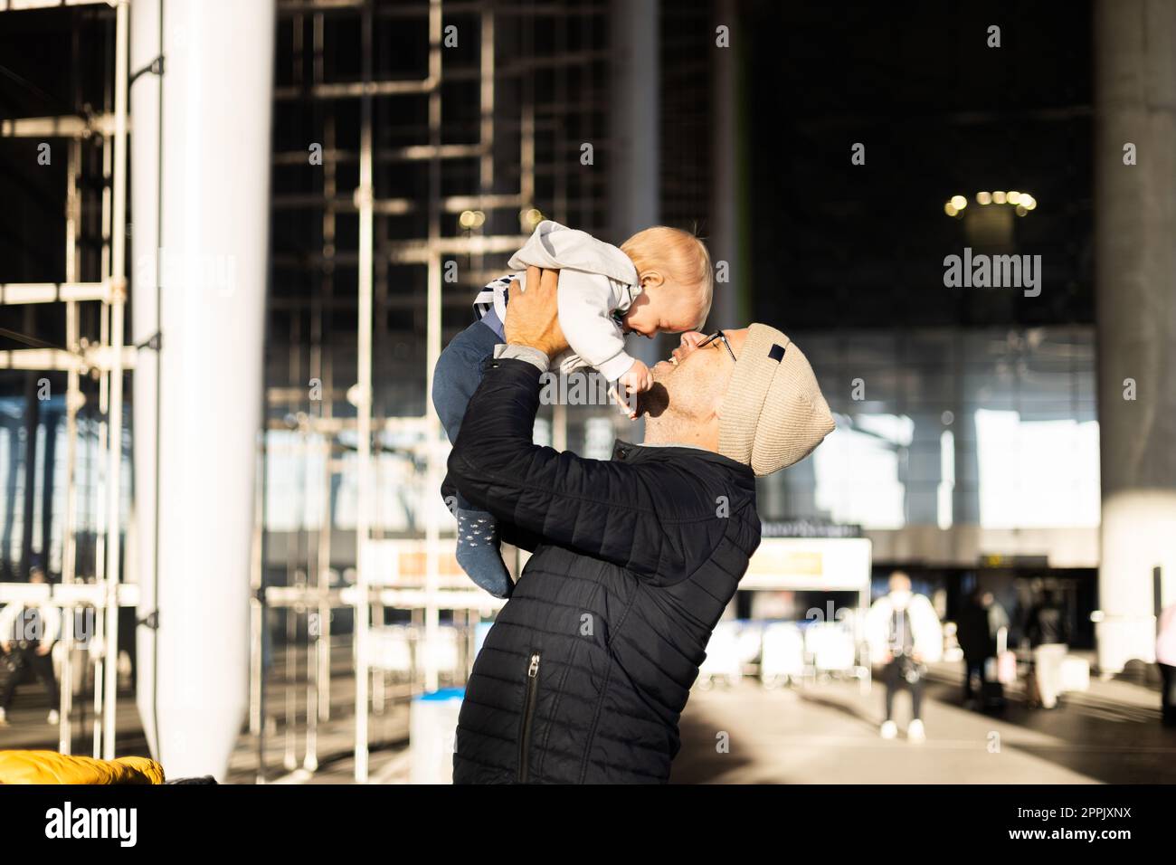 Il padre è felice di tenere e sollevare il bambino in aria dopo essere stato riunito di fronte alla stazione del terminal dell'aeroporto. Concetto di viaggio per bambini. Foto Stock