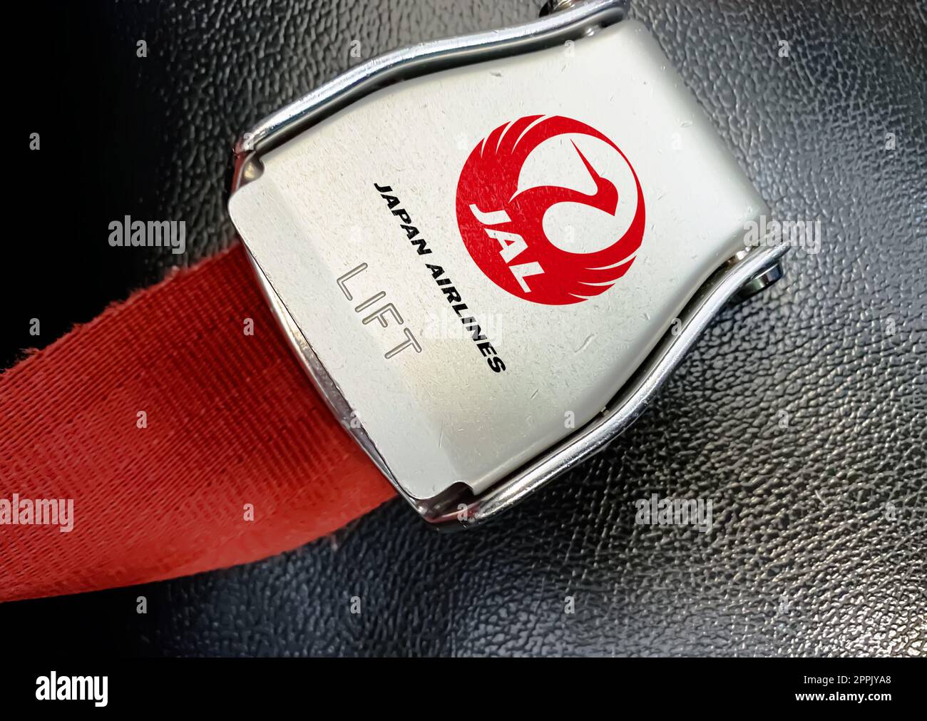 Dettaglio della fibbia della cintura di sicurezza con il logo di Japan Airlines su un sedile vuoto Foto Stock