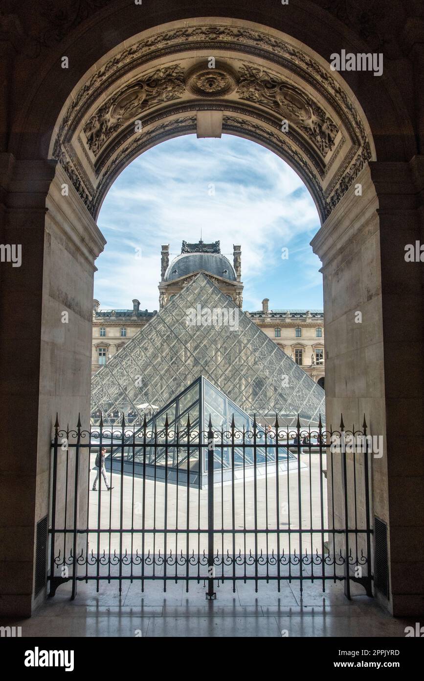 Vista attraverso un arco dell'ala sinistra del Palazzo del Louvre fino alla Piramide di vetro, Parigi Foto Stock