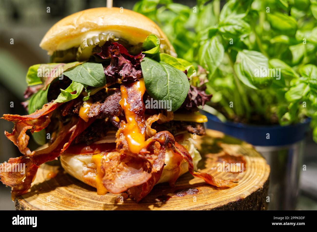 Elegante hamburger con formaggio e pancetta servito su un vassoio rustico di legno Foto Stock