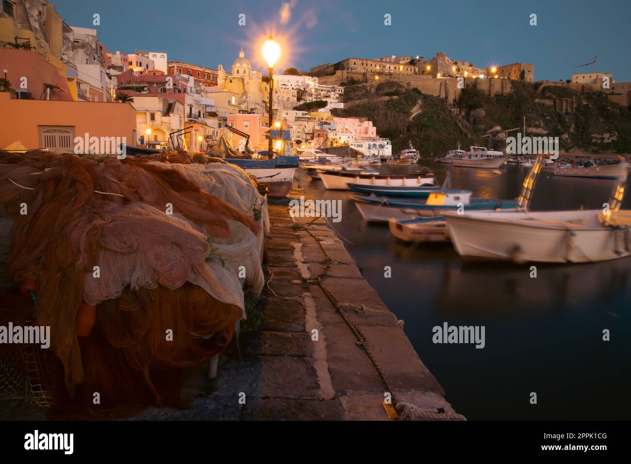 Colorate reti da pesca a Marina Corricella nell'ora blu sull'isola di Procida, Golfo di Napoli, Italia. Foto Stock