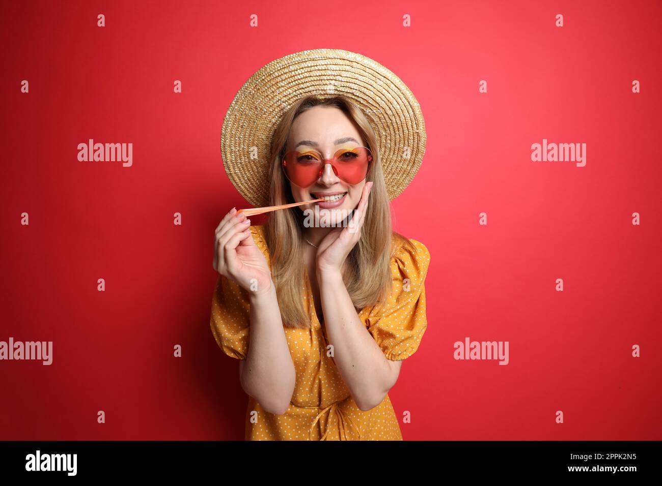 Giovane donna alla moda masticare bubblegum su sfondo rosso Foto Stock