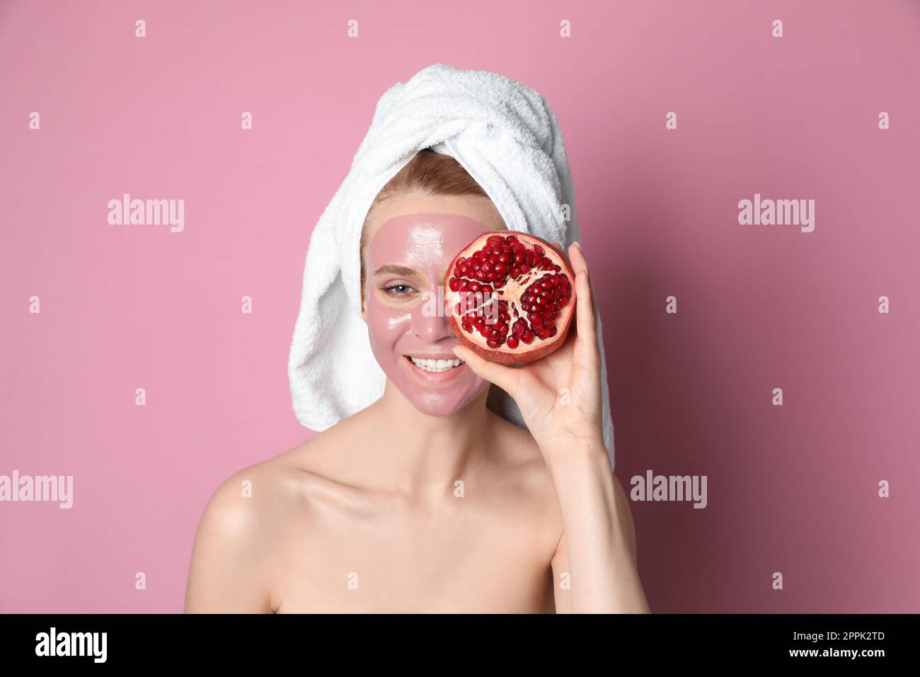 Giovane donna con maschera di melograno e frutta fresca su sfondo rosa Foto Stock