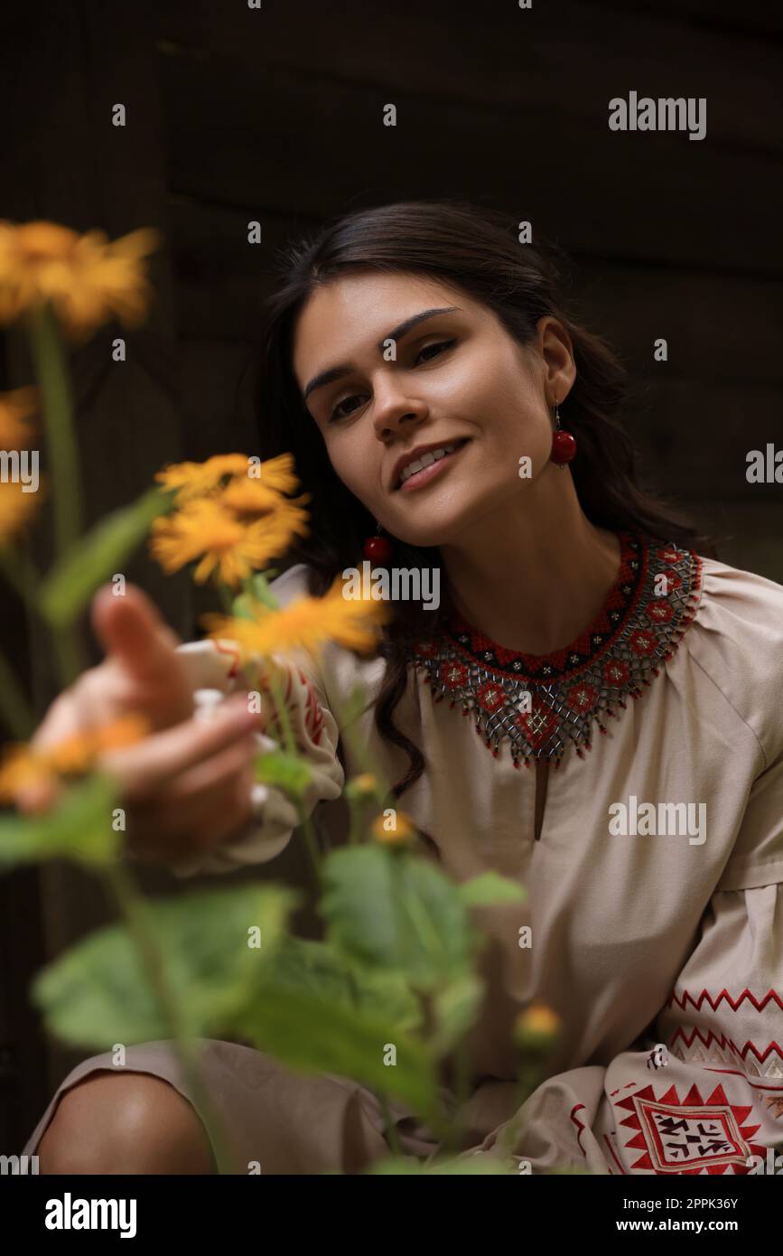 Bella donna vestito ricamato in giardino fiorito. Vestiti nazionali ucraini Foto Stock