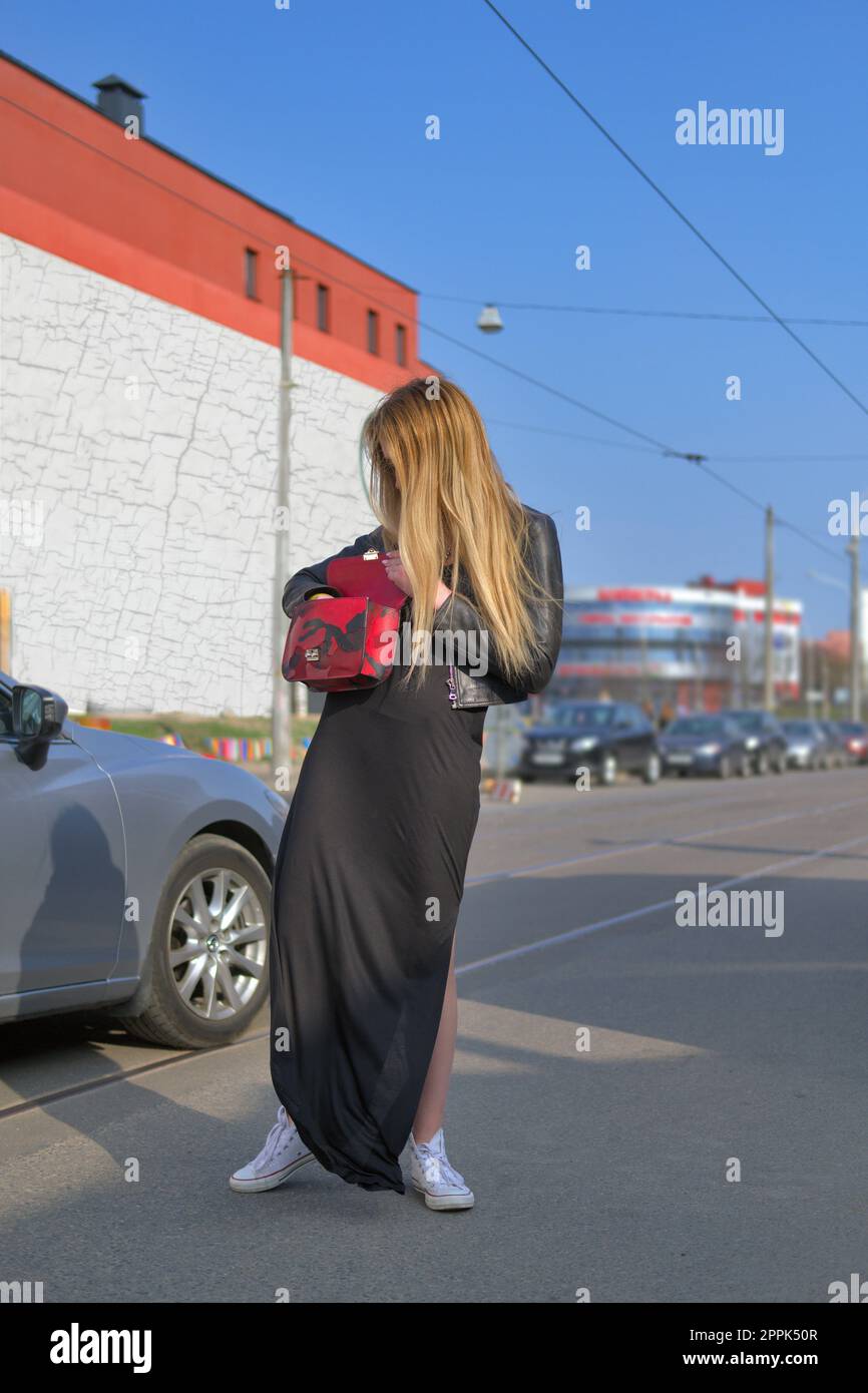 Giovane donna cercando la chiave dalla sua auto in borsa Foto Stock