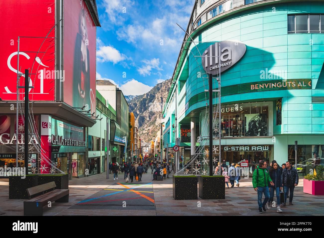 Una folla di persone che camminano e fanno shopping sul lungomare con i Pirenei sullo sfondo, Andorra Foto Stock